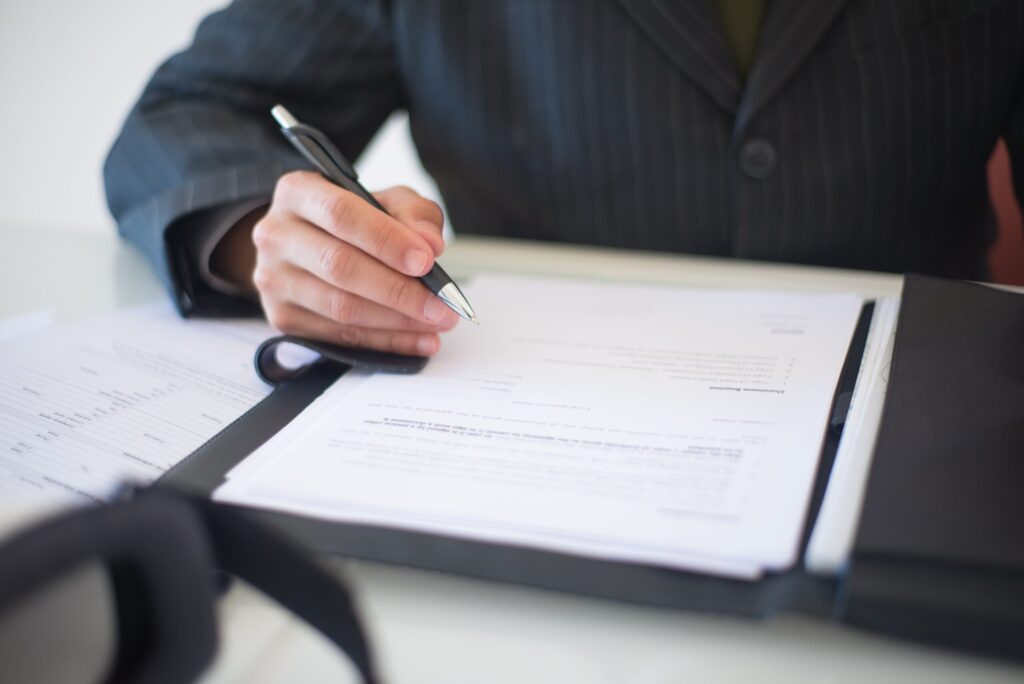 Person signing documents with a pen